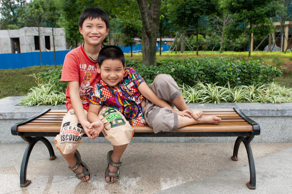 Two boys sitting together on a bench