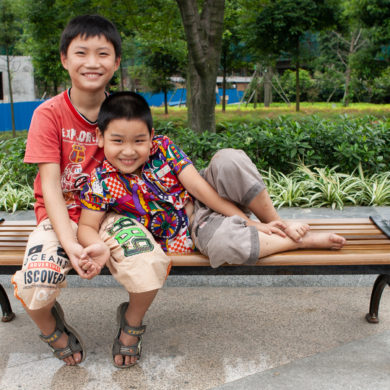 Two boys sitting together on a bench