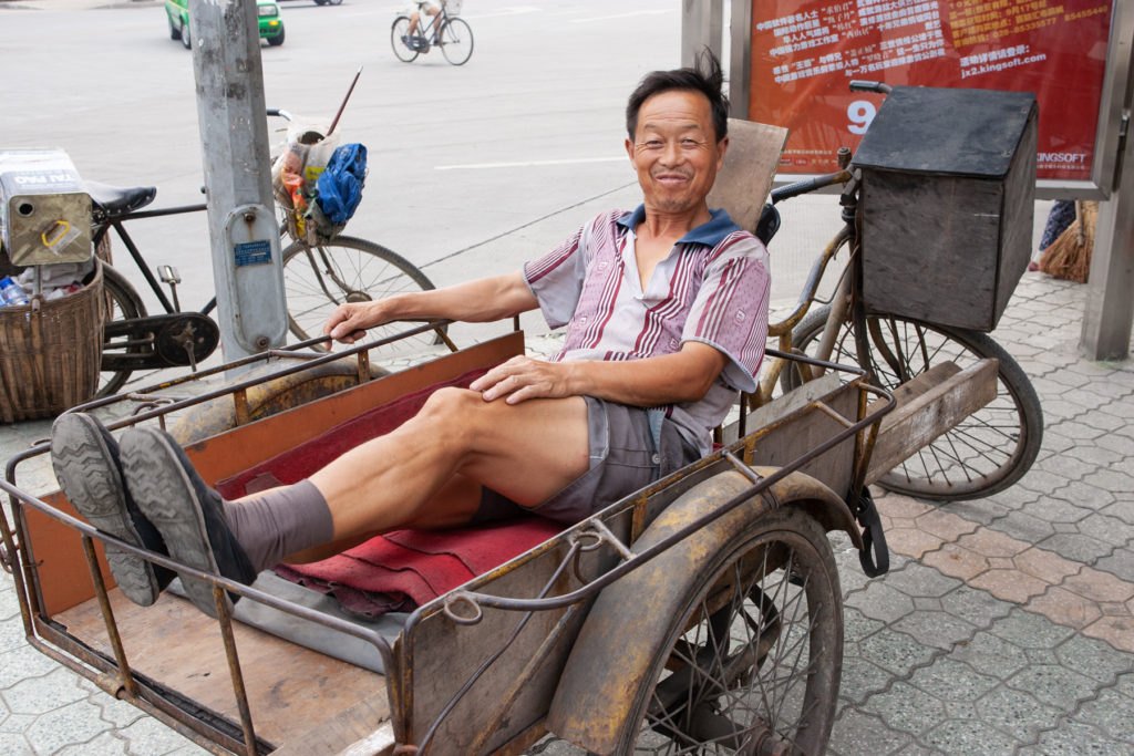 Man sitting in bed of cargo tricycle