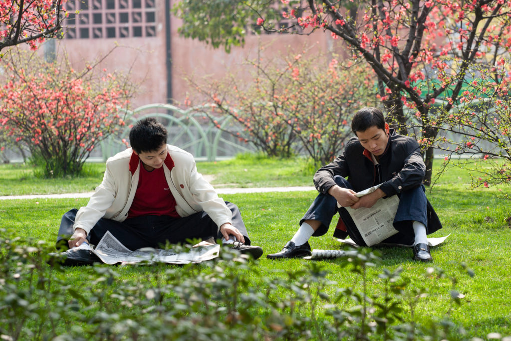 Two men reading newspapers in the park