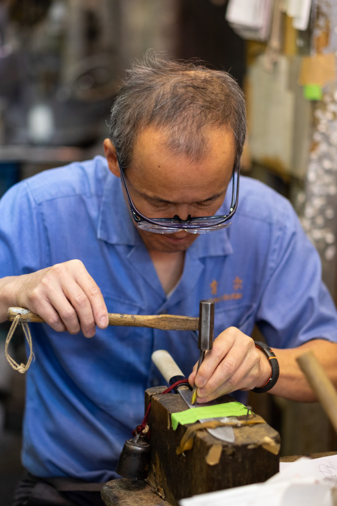 Man engraving knife with hammer and punch