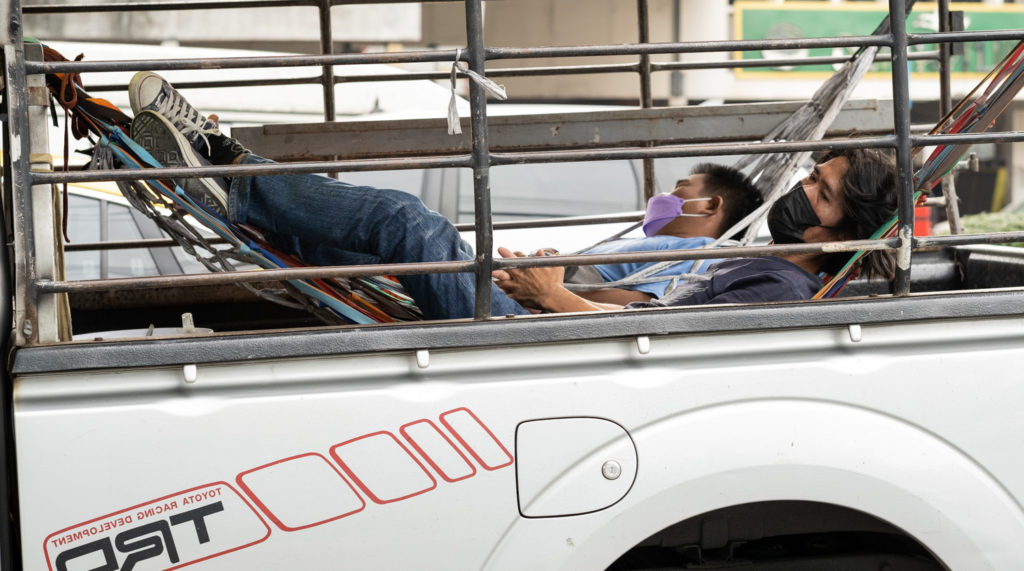 Two men in hammocks in the back of a pickup truck