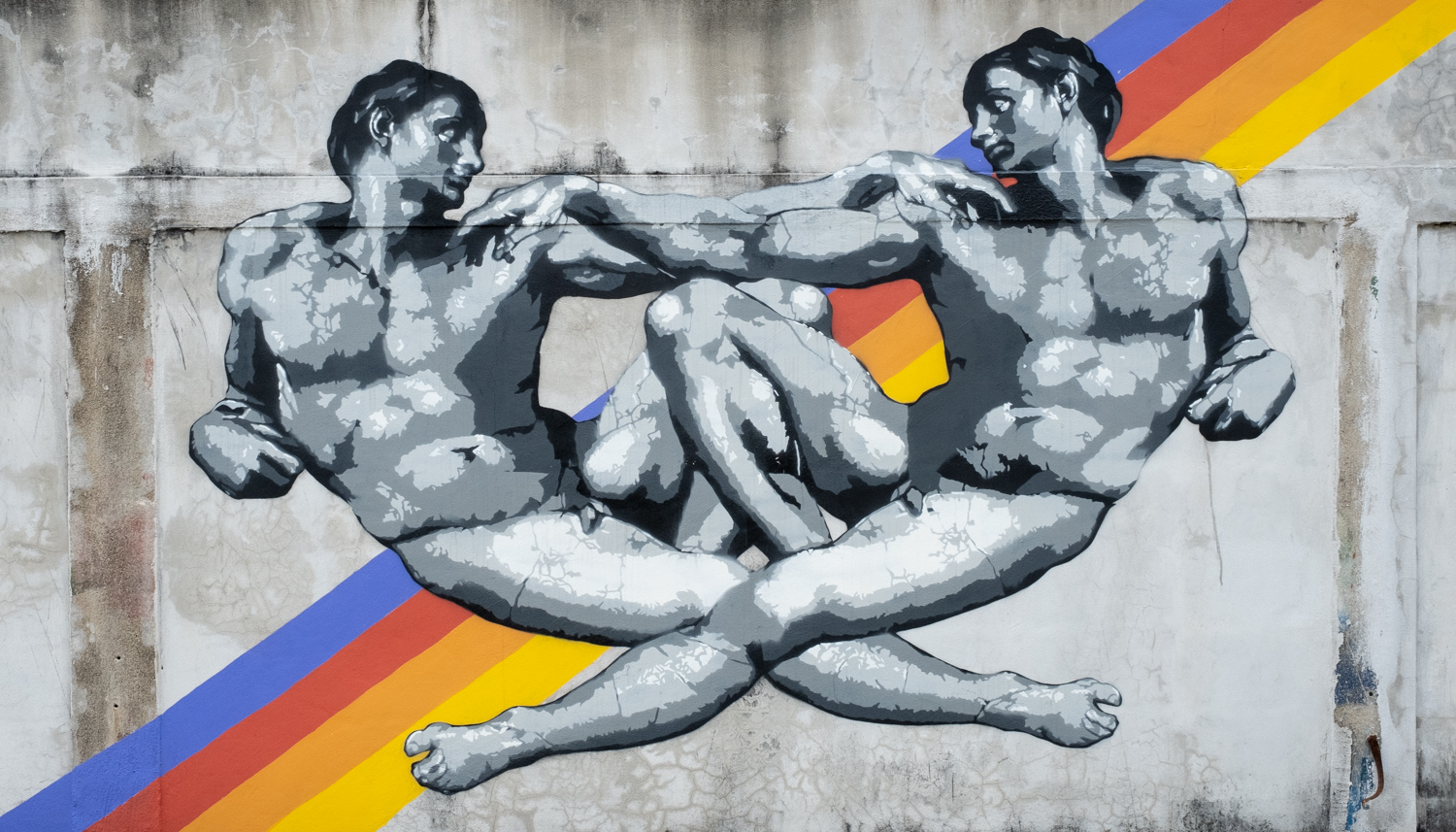 bansky-inspired graffiti of two naked men whose bodies roughly form a heart, with a rainbow-like design behind