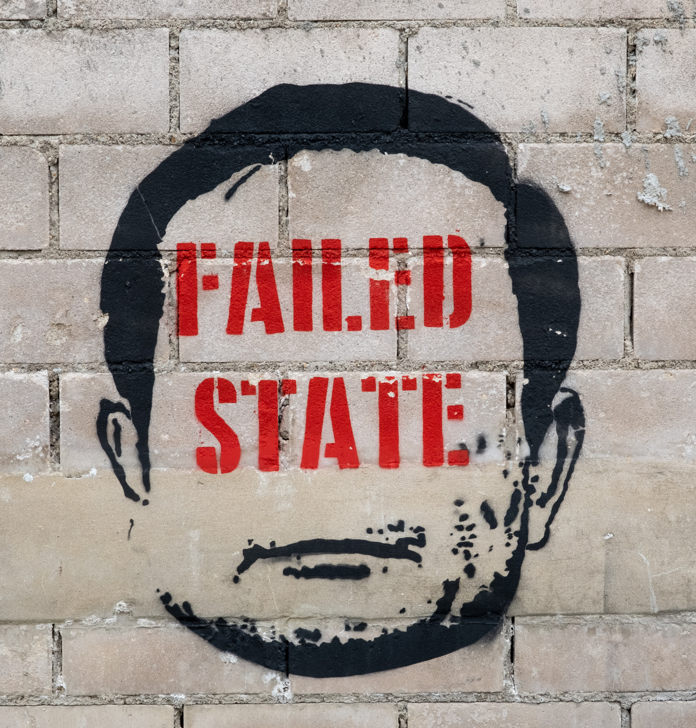 graffiti outline of a man's head with "failed state" stenciled where his face would be