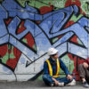 two workers on a break in front of of colorful graffiti of stylized writing