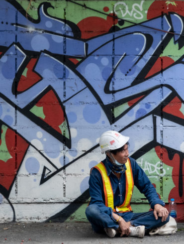 two workers on a break in front of of colorful graffiti of stylized writing