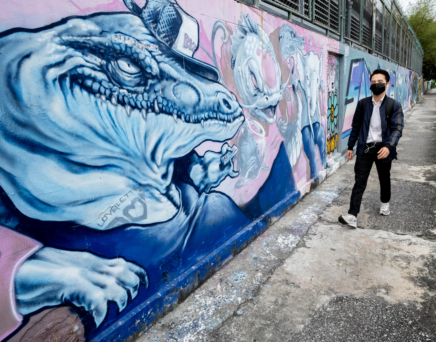 graffiti of an alligator with a man walking near it