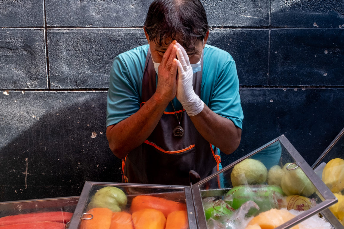 Fruit vendor offering a blessing by placing his hands in a praying position in front of his face