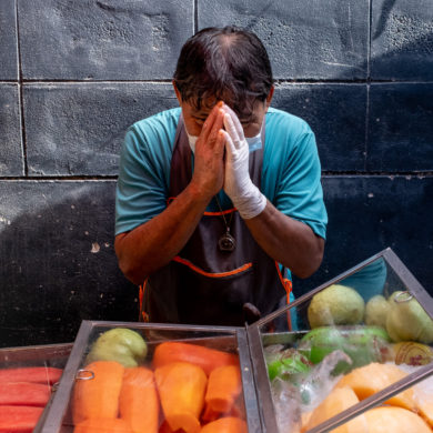 Fruit vendor offering a blessing by placing his hands in a praying position in front of his face