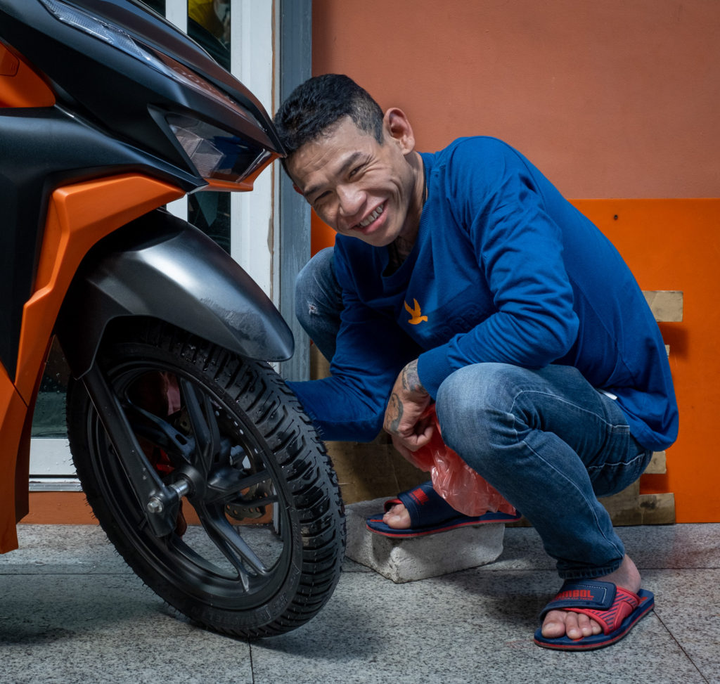 man working on the front wheel of a scooter