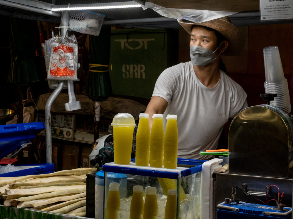 man wearing cowboy hat selling sugar cane juice