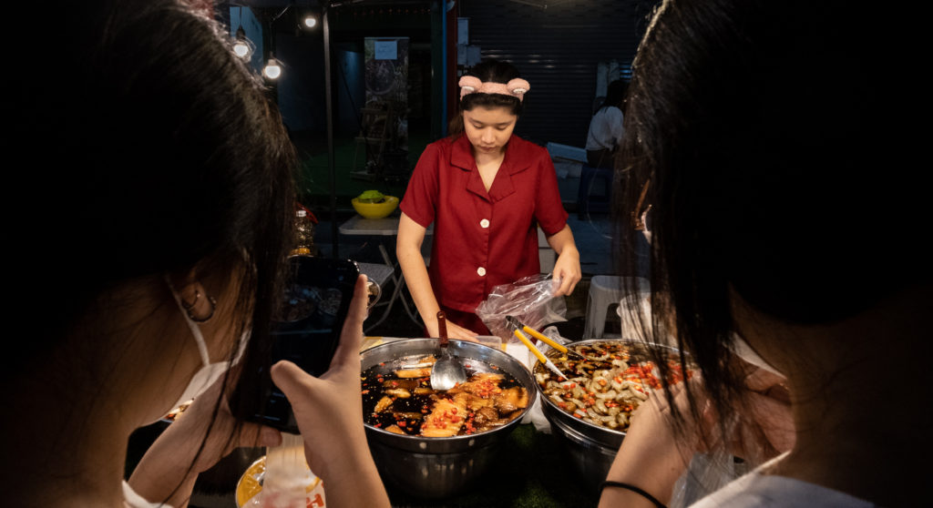 woman with mouse ear headband selling food to two young women