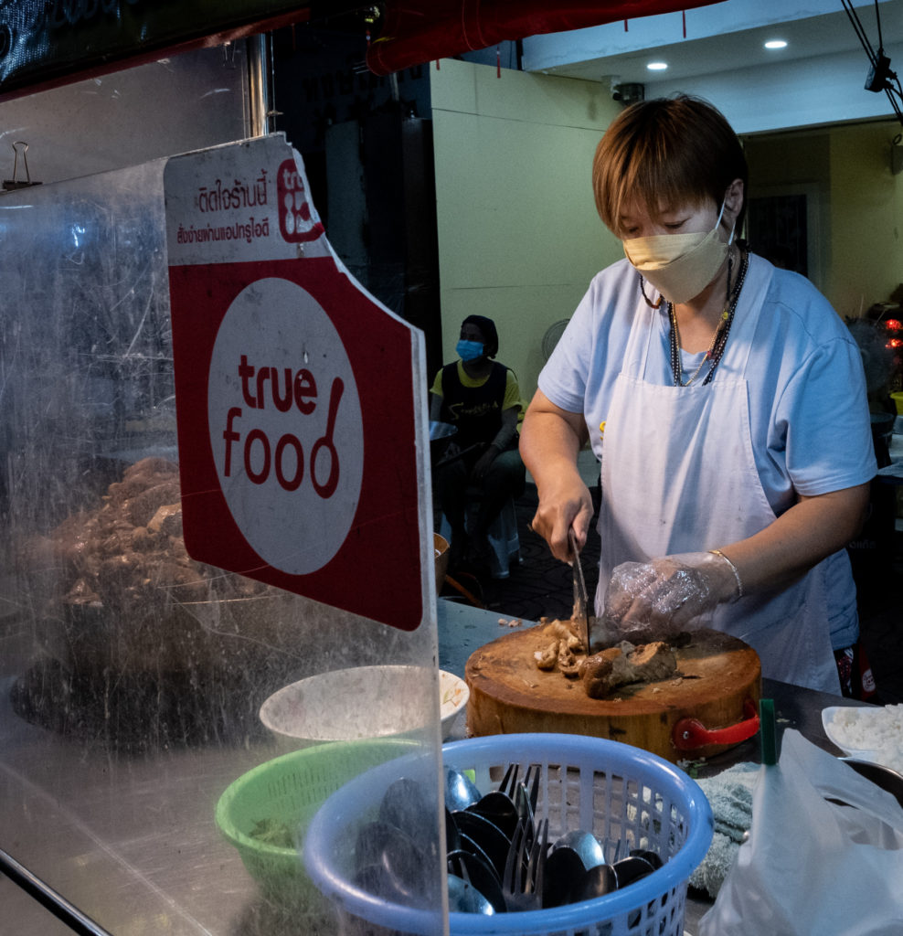 woman with apron chopping meat on a wood roumd