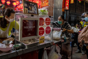 streetside restaurant with three women has Michelin Star signs