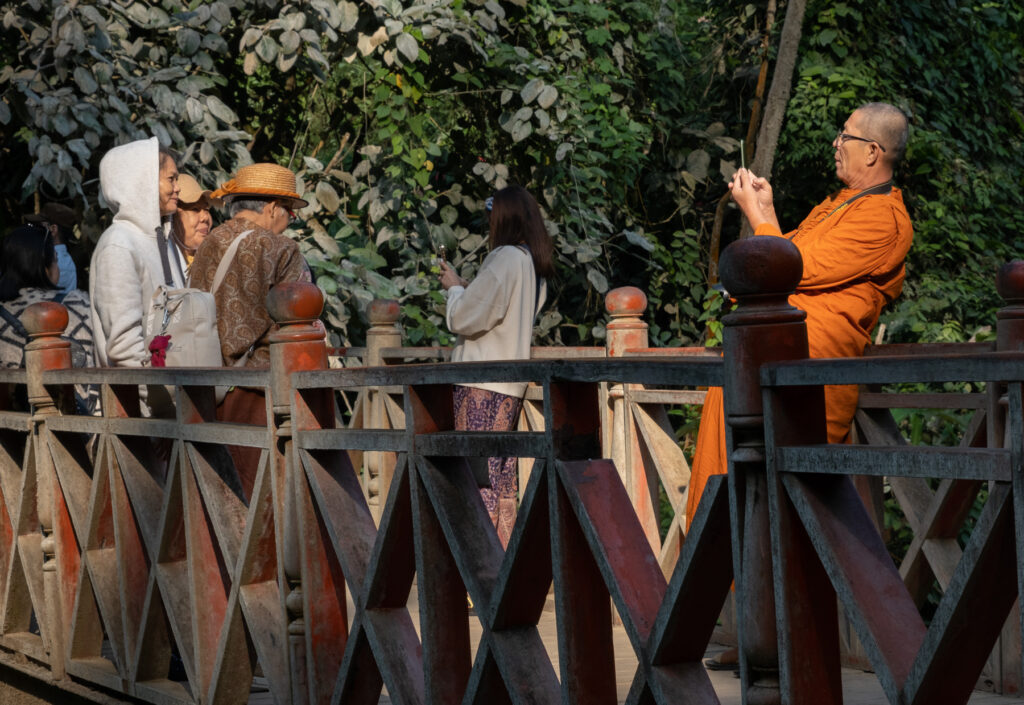 People on a bridge with Buddhist monk snapping picture of friends