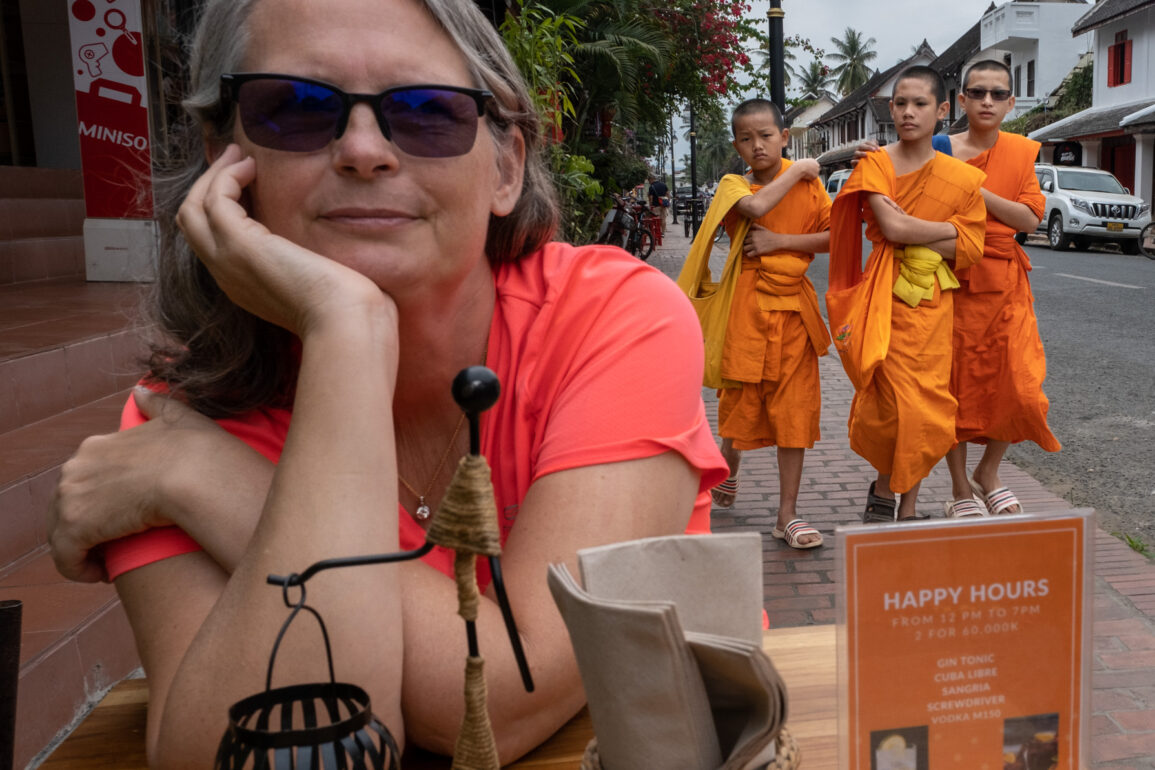 woman sitting at table with three young monks behind her