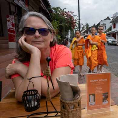 woman sitting at table with three young monks behind her